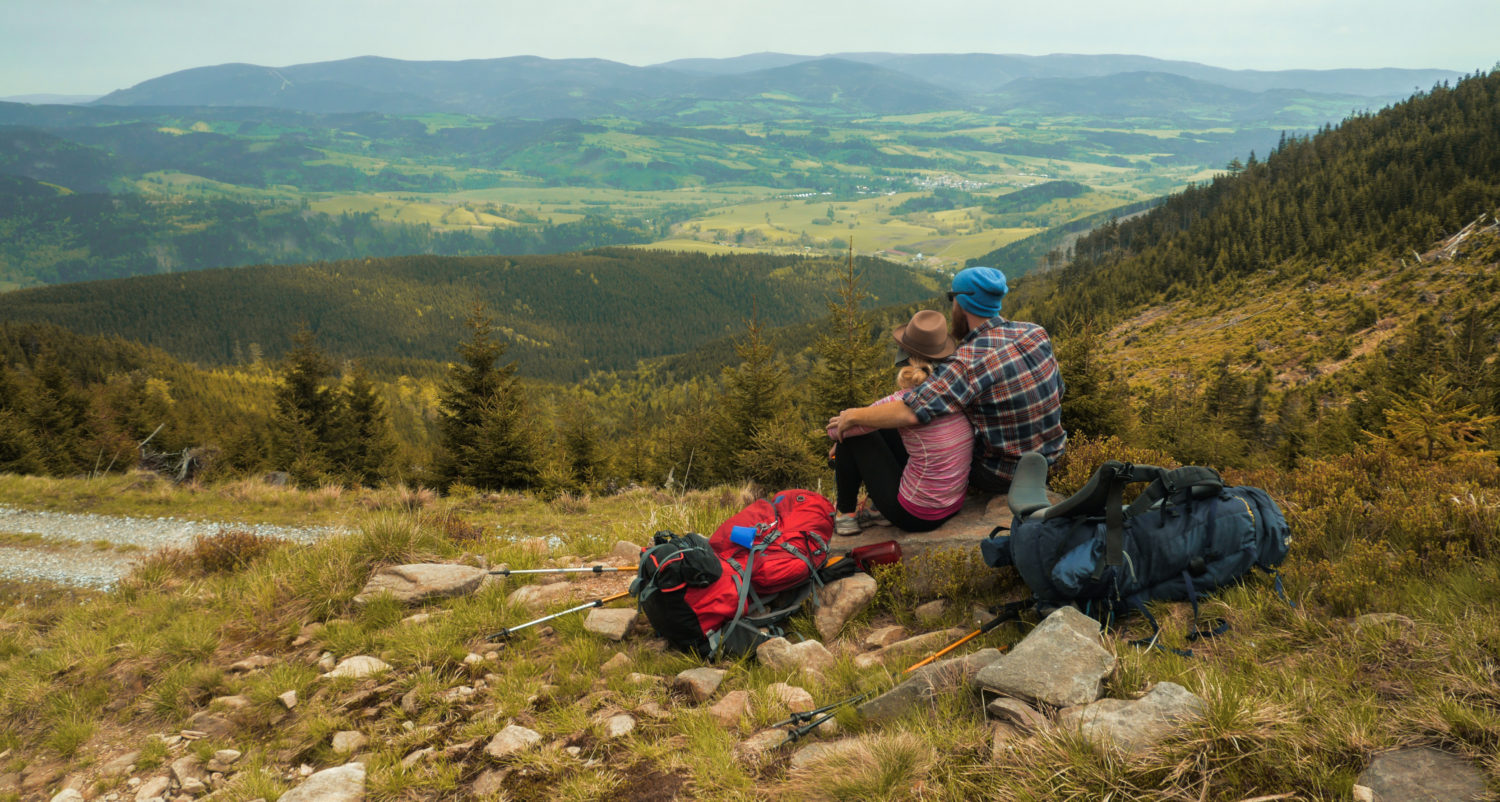 A couple sitting together enjoying a view of hilly Czech Republic countryside while walking from Prague to Budapest