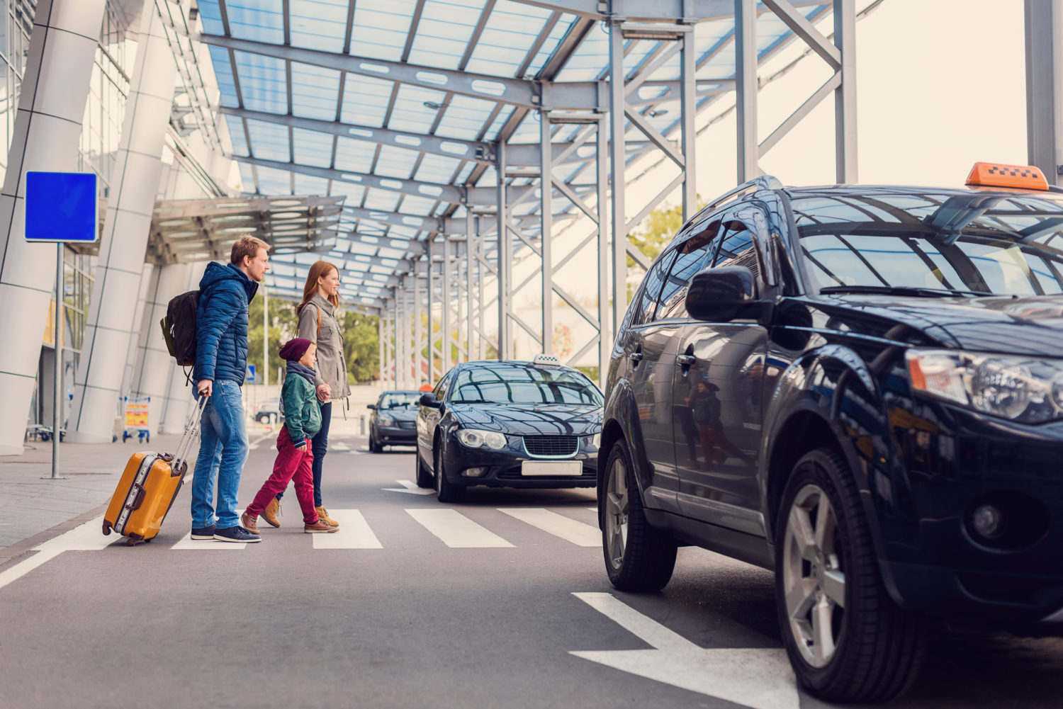 Family crossing the road towards parked cars for private transfer from Prague to Karlovy Vary