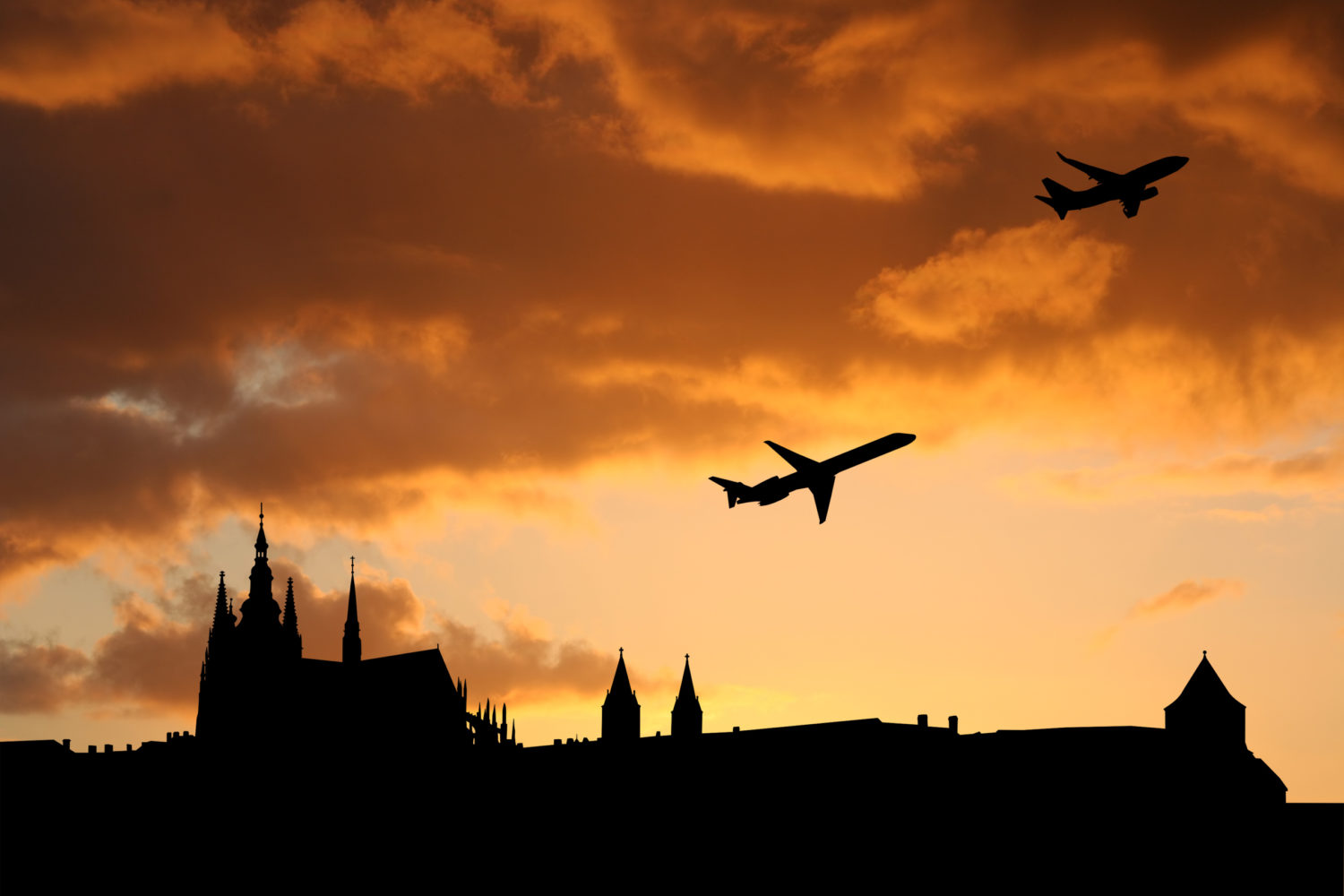 Two airplanes flying over a city going from Prague to Budapest