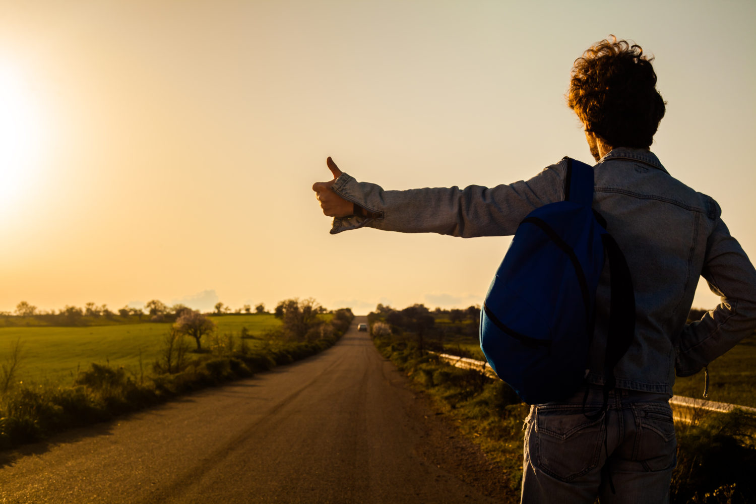 Man with a backpack hitchhiling on a road from Lisbon to Porto 