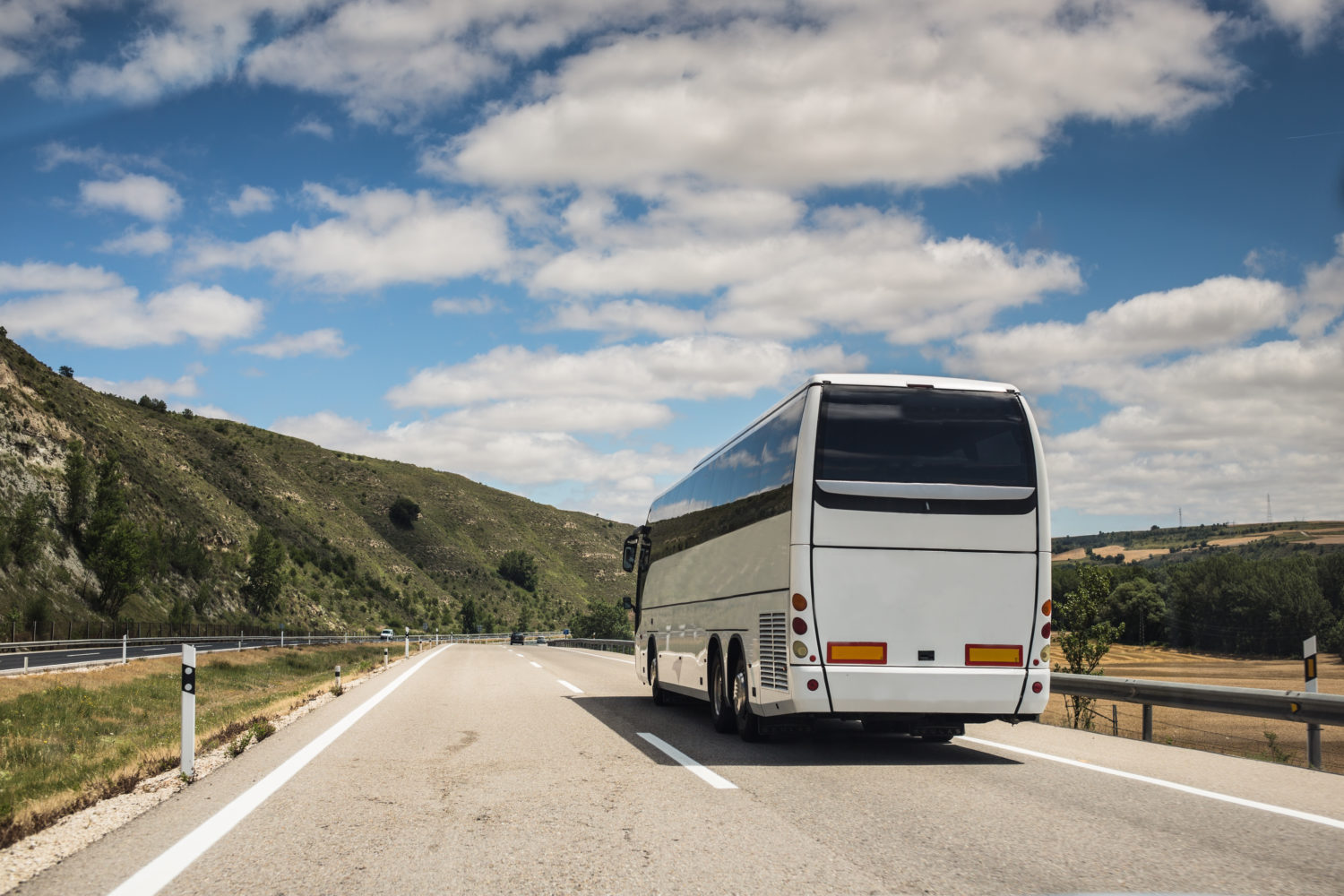 White bus on a road in hilly countyside 