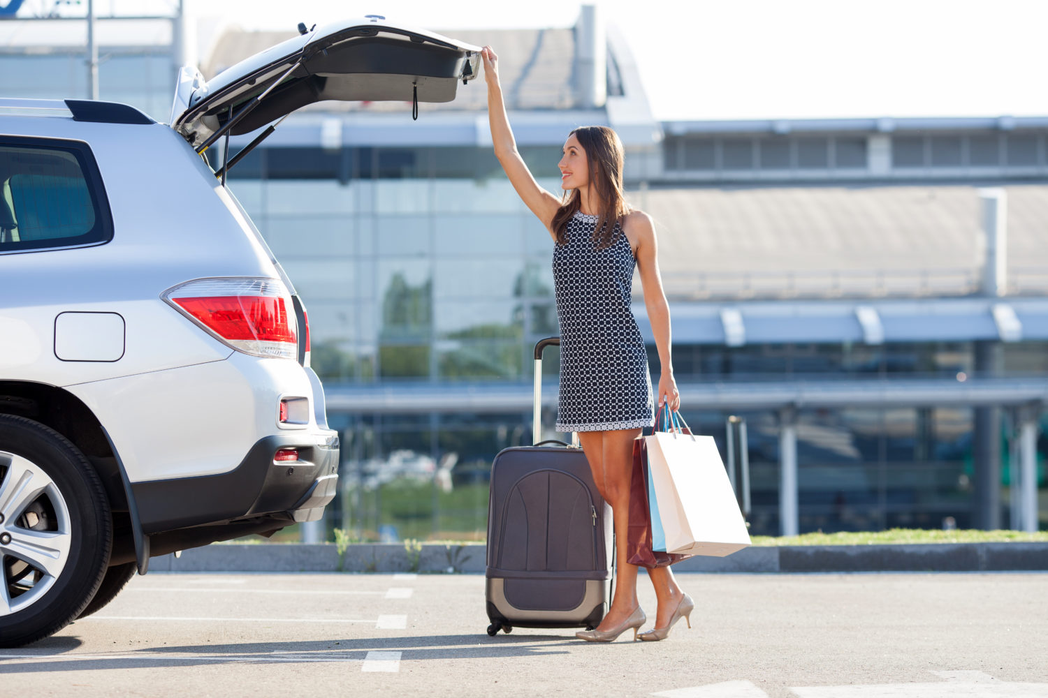 Young professional woman with bags next to a private transfer car from Prague to Vienna