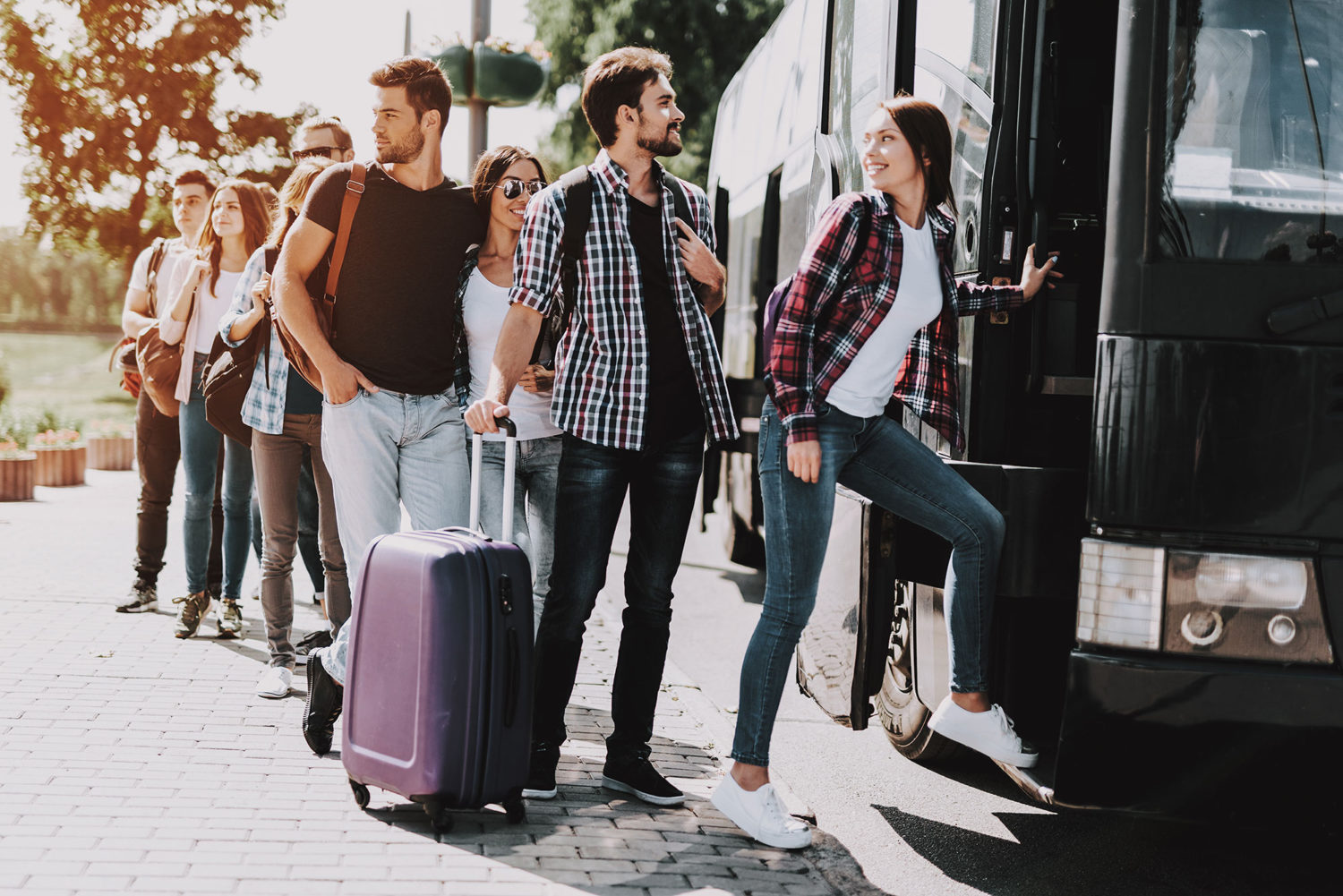 Group of young travellers getting on a black bus