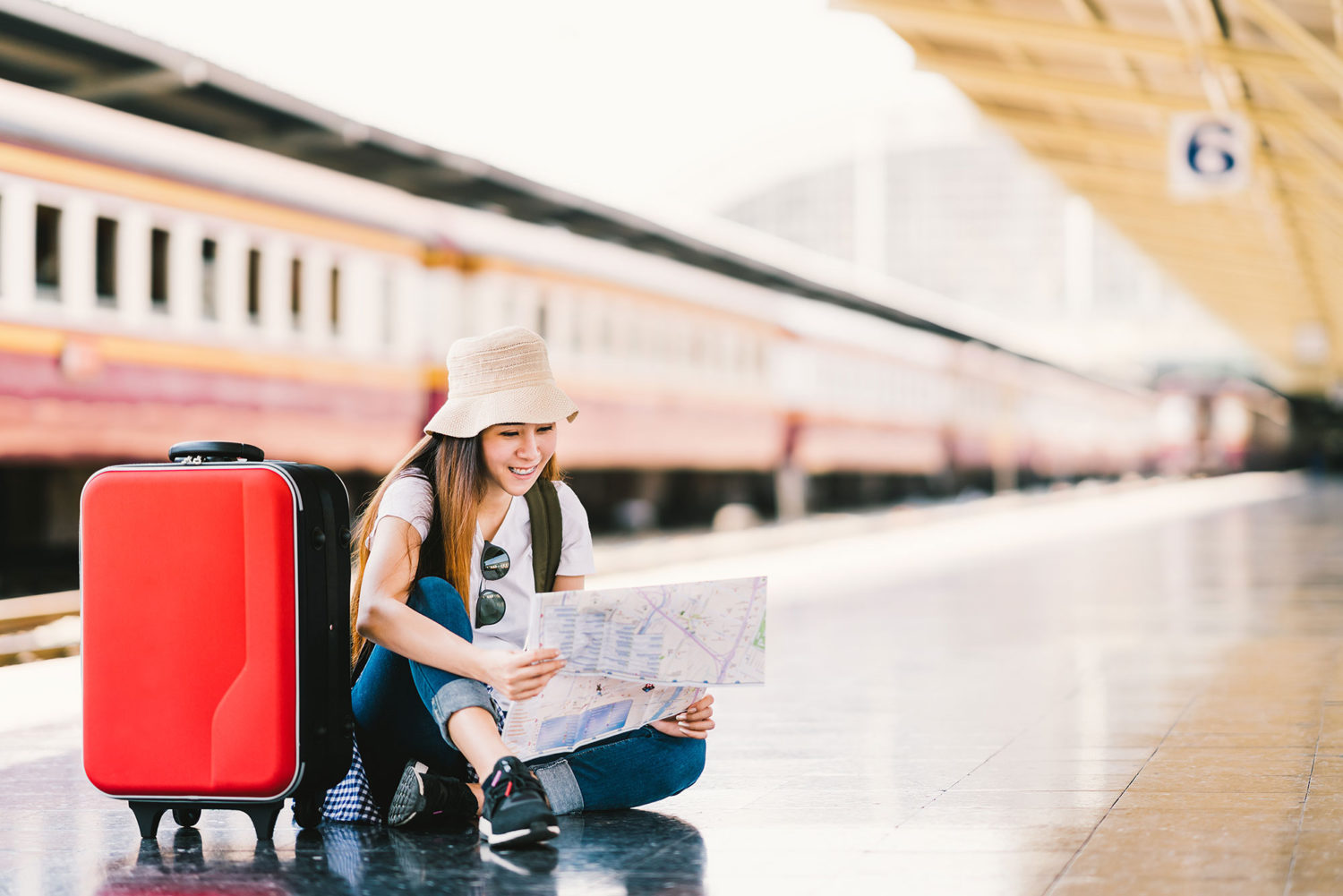 Woman in a hat reading a map seated on a train platform