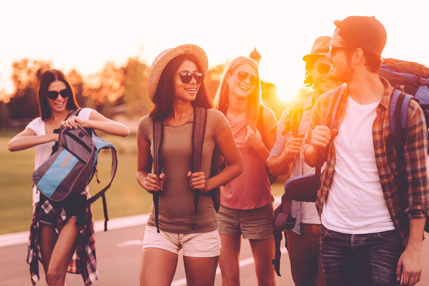 Group of young people walking on a road during sunset